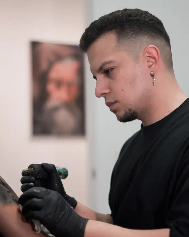 fotografía de Jhon Valenzia tatuando a un cliente